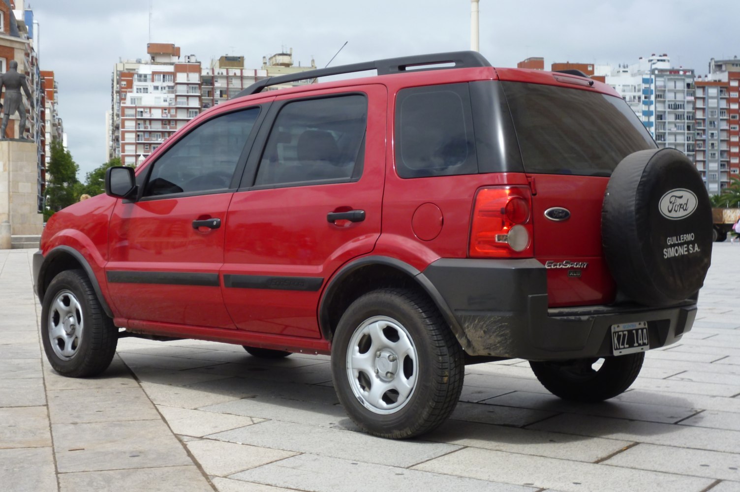Red compact SUV with rear spare tire and roof rack