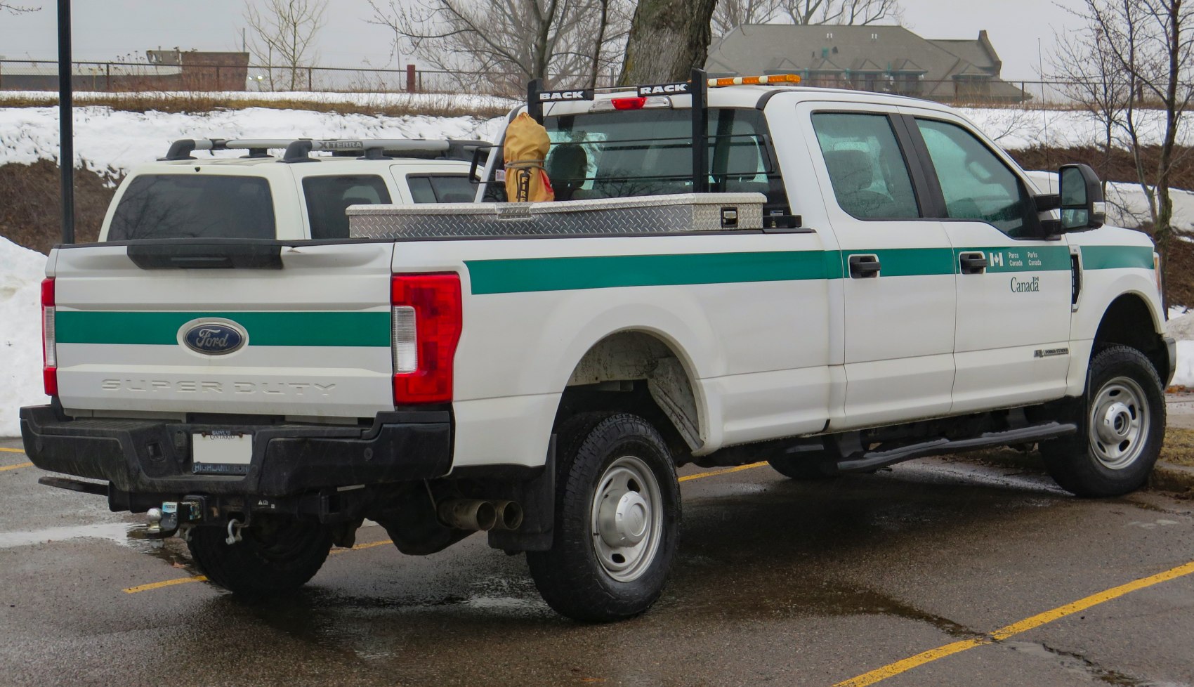 White pickup with crew cab and long utility bed with toolbox and rack