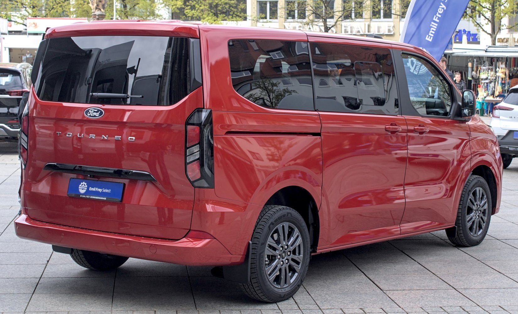 Red passenger van rear side with tinted windows and modern taillights