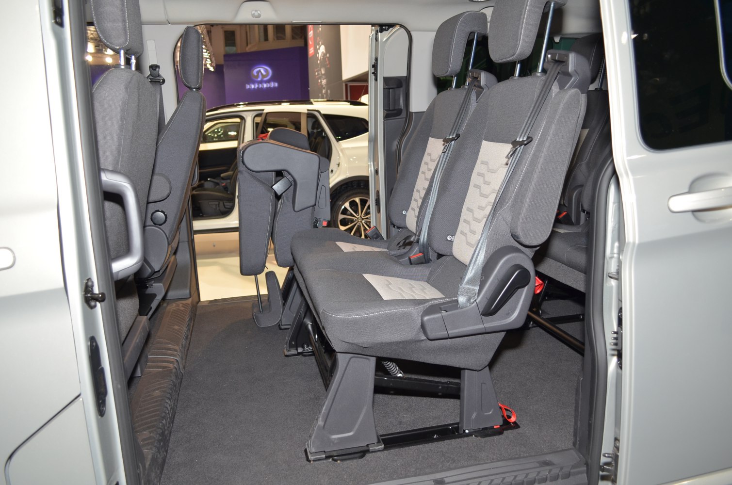 Passenger seats with armrests and adjustable headrests inside a vehicle.