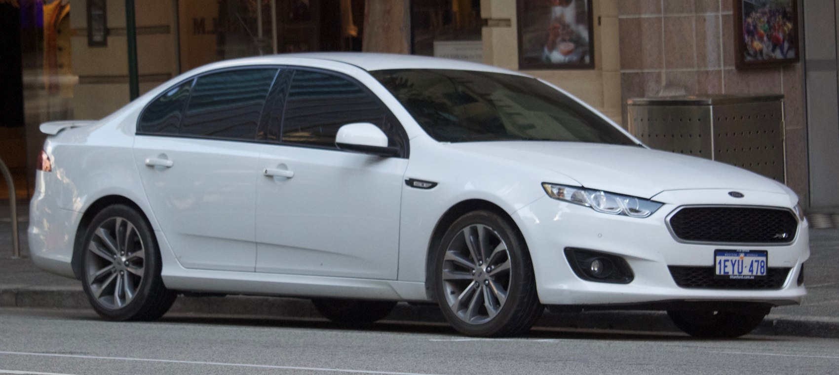 White sedan with black grille, tinted windows, sporty alloy wheels