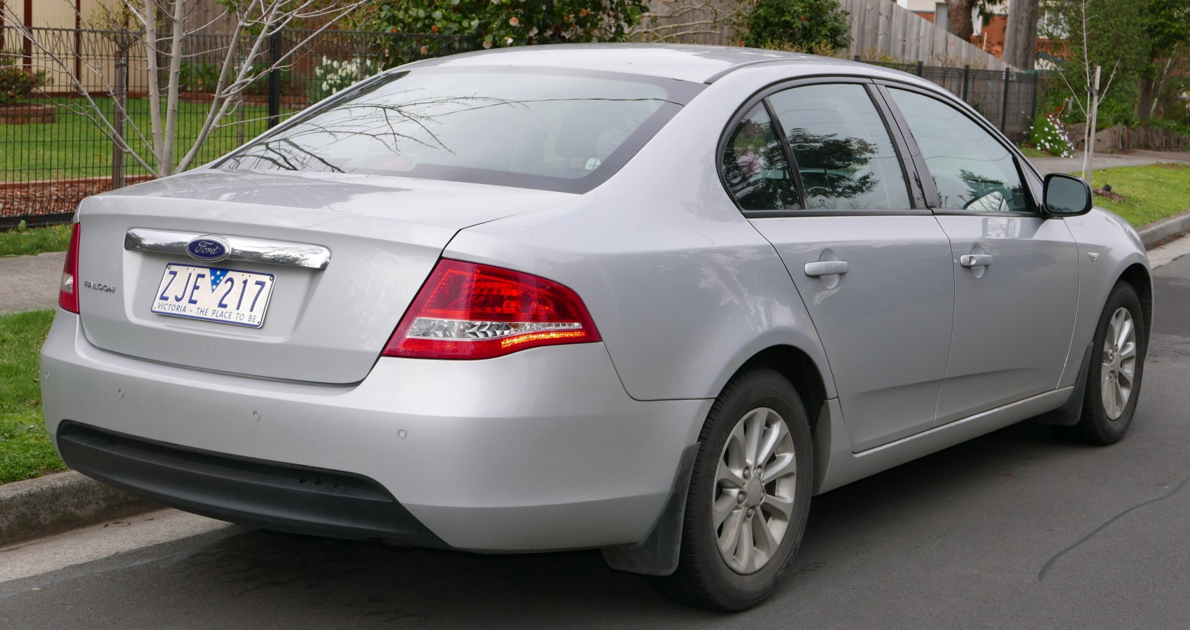 Rear and side view of silver four-door sedan with alloy wheels and illuminated tail light.