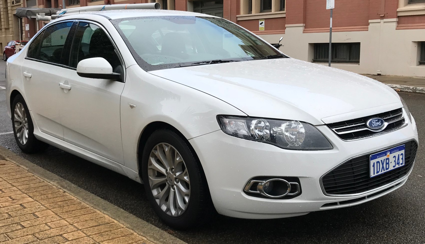White sedan front side view with headlights and alloy wheels