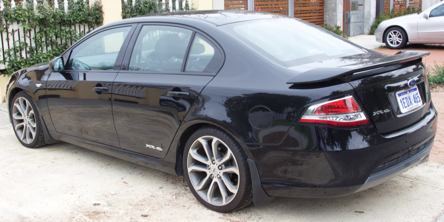 Rear side view with alloy wheels and spoiler of a sporty sedan