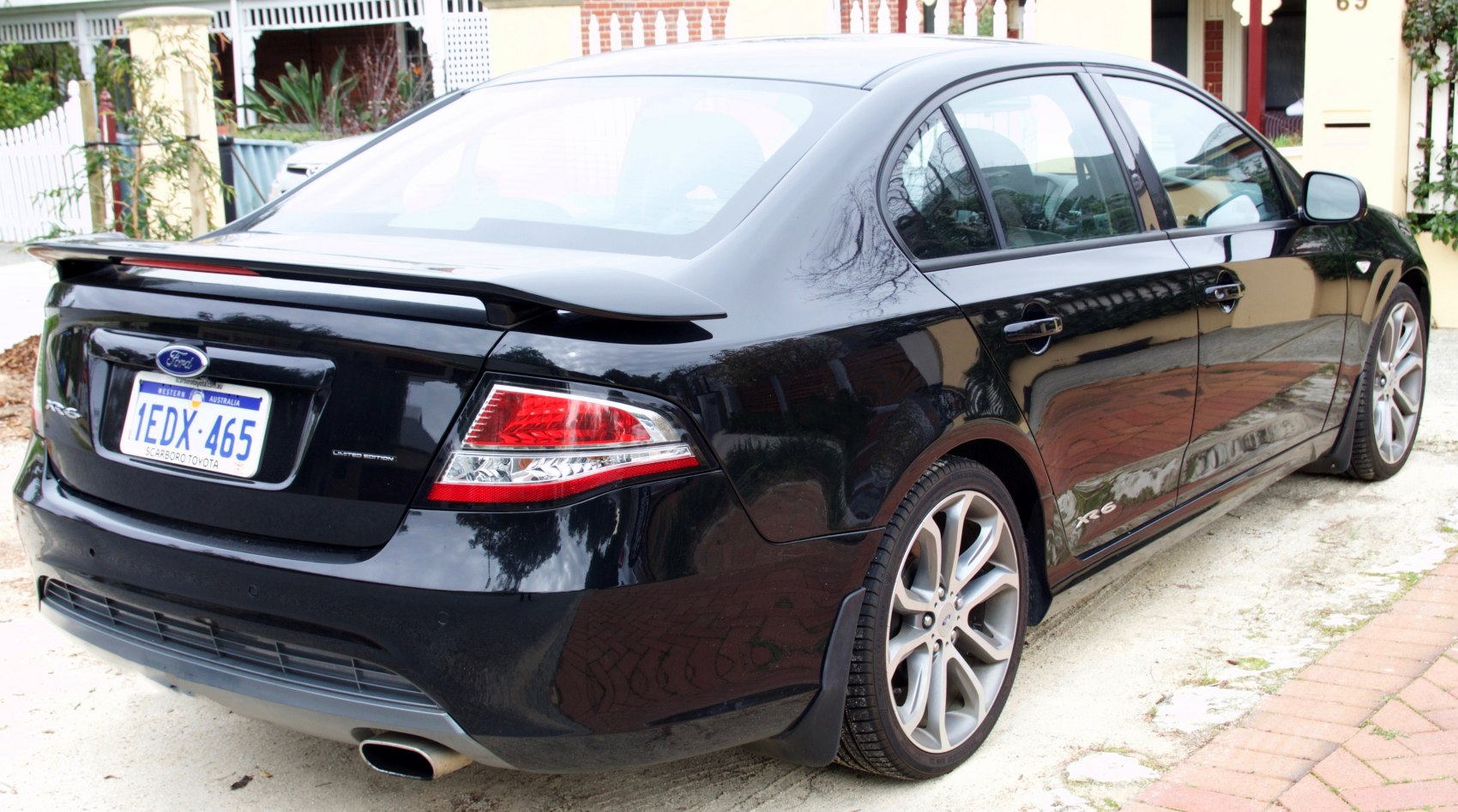 Rear and side view of a black sedan with spoiler and alloy wheels