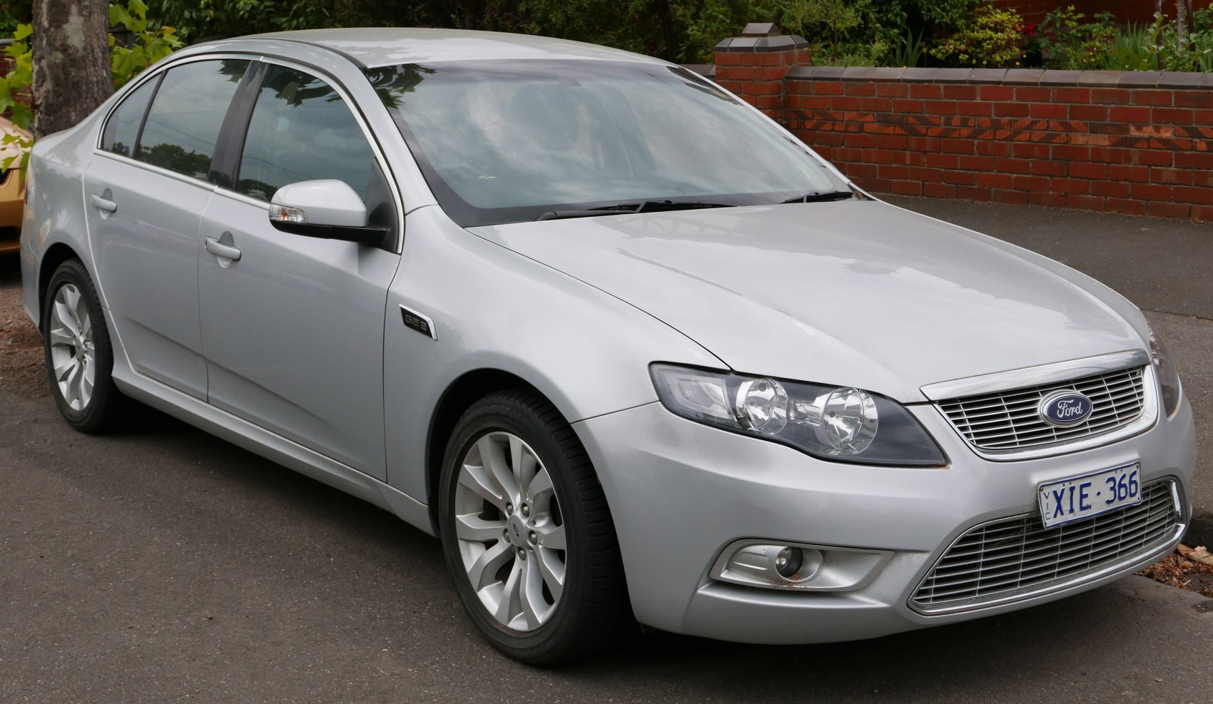 Silver sedan front side with dual headlights and alloy wheels.