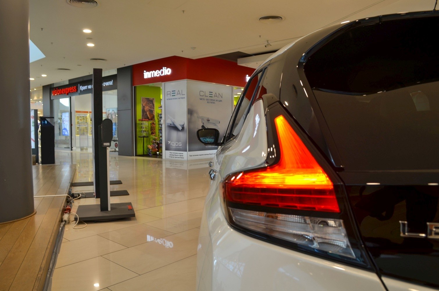 Close-up of illuminated rear left taillight and side mirror in indoor setting