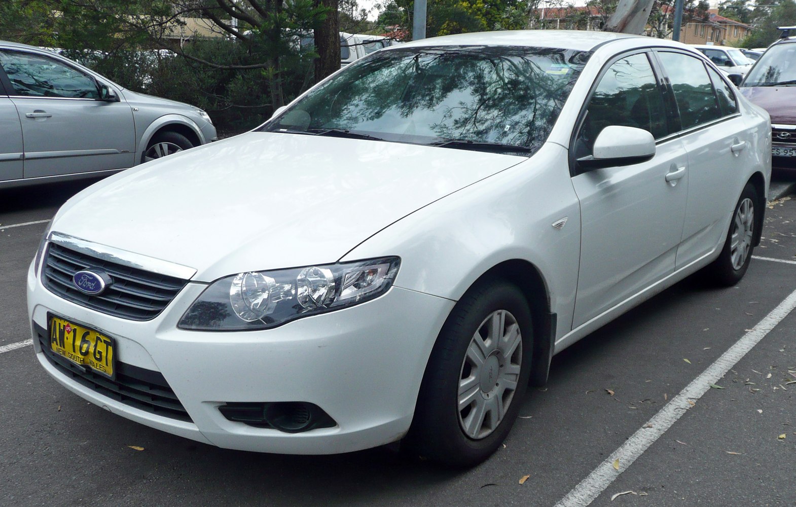 White sedan front side with headlight and grille details