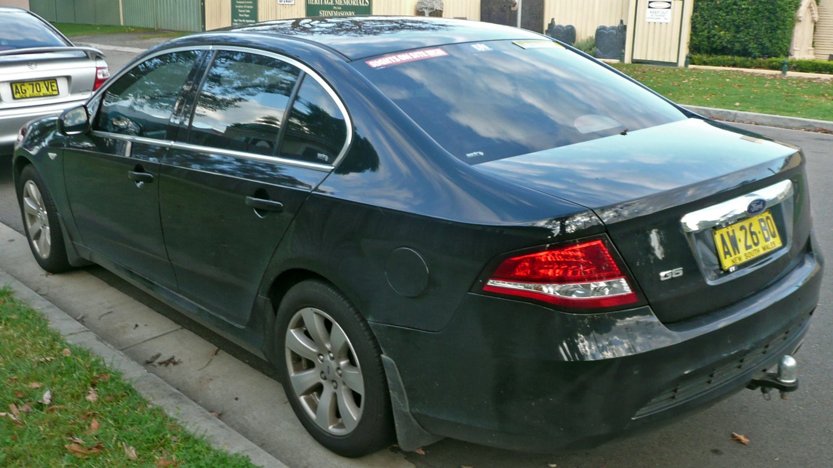 Rear side of a black four-door sedan with visible taillights and tow hitch
