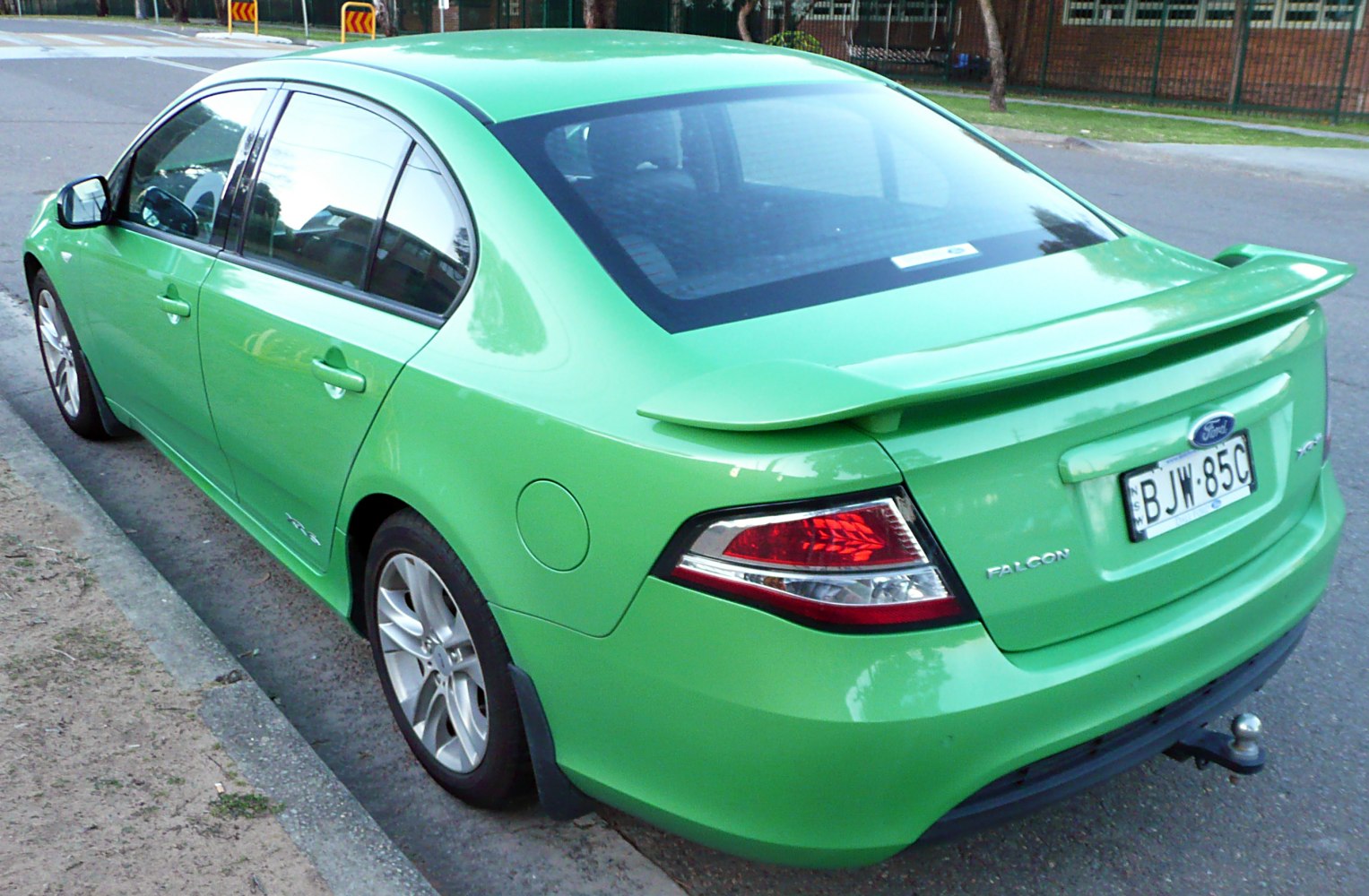 Rear side view of green sedan with prominent spoiler and alloy wheels