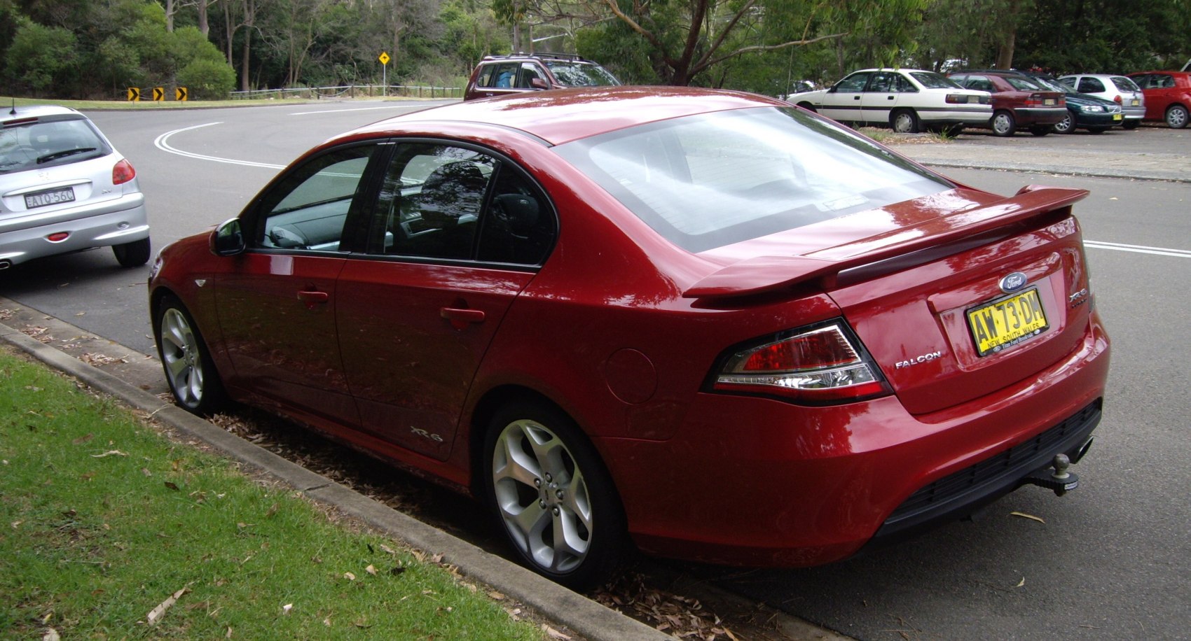 Rear-side view of a red sedan with sporty spoiler and alloy wheels