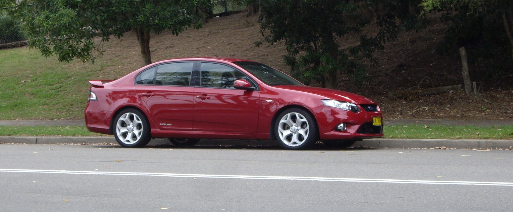 Red sedan with rear spoiler and five-spoke alloy wheels