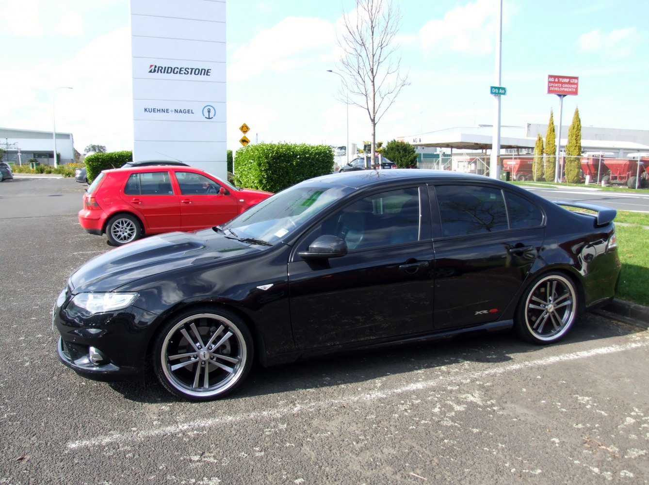 Black sedan with spoiler and alloy wheels parked outdoors