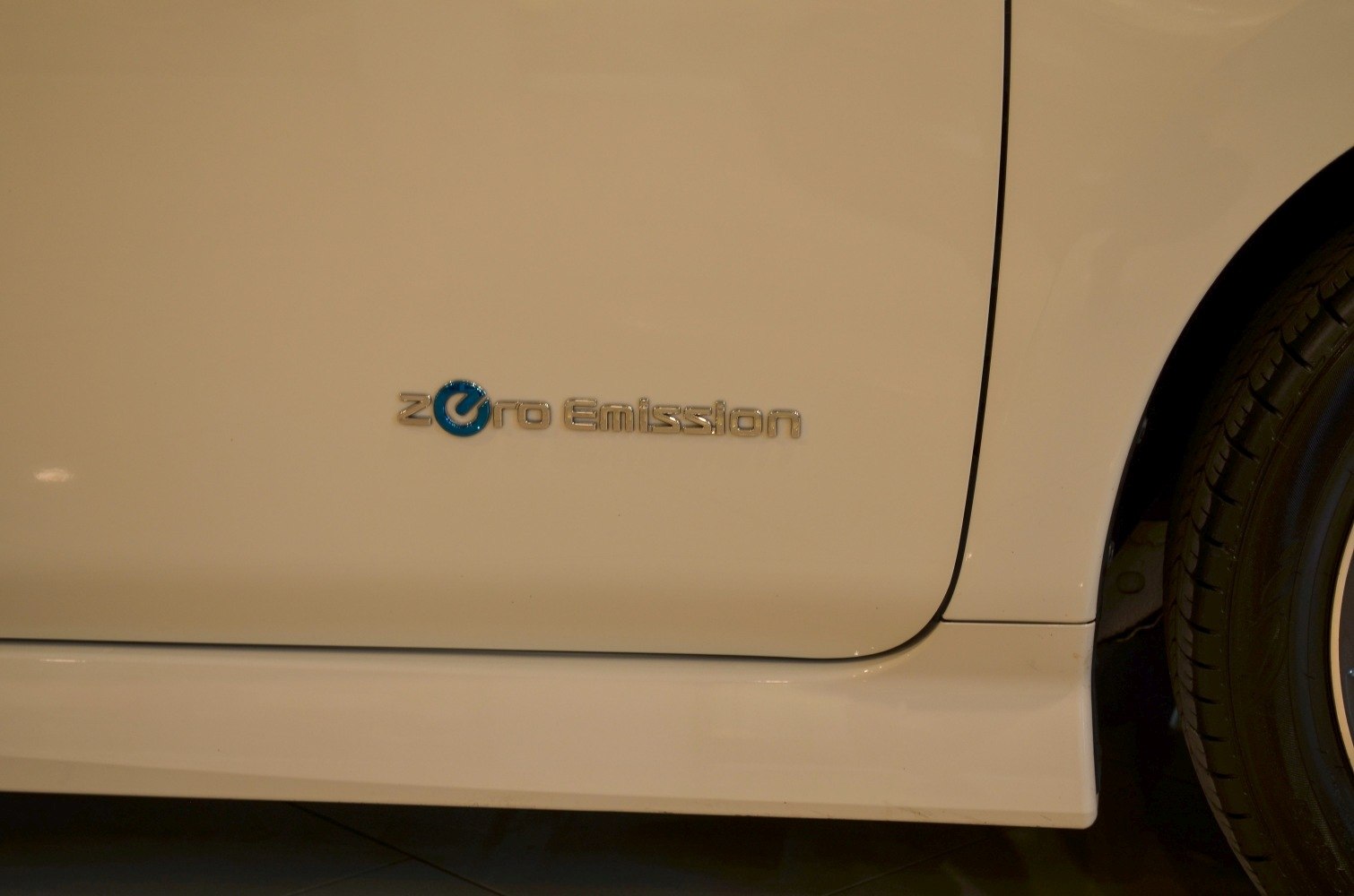 Close-up of zero emission emblem on vehicle side panel near rear wheel.