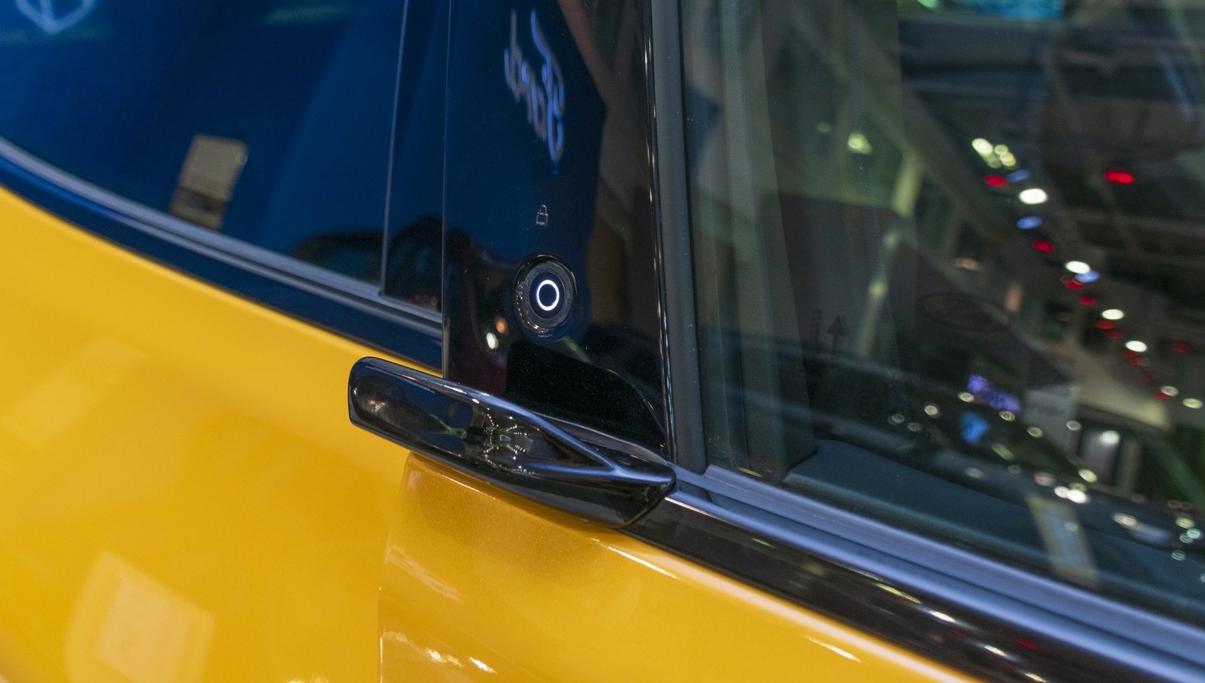 Close-up of door handle and side camera on a yellow vehicle