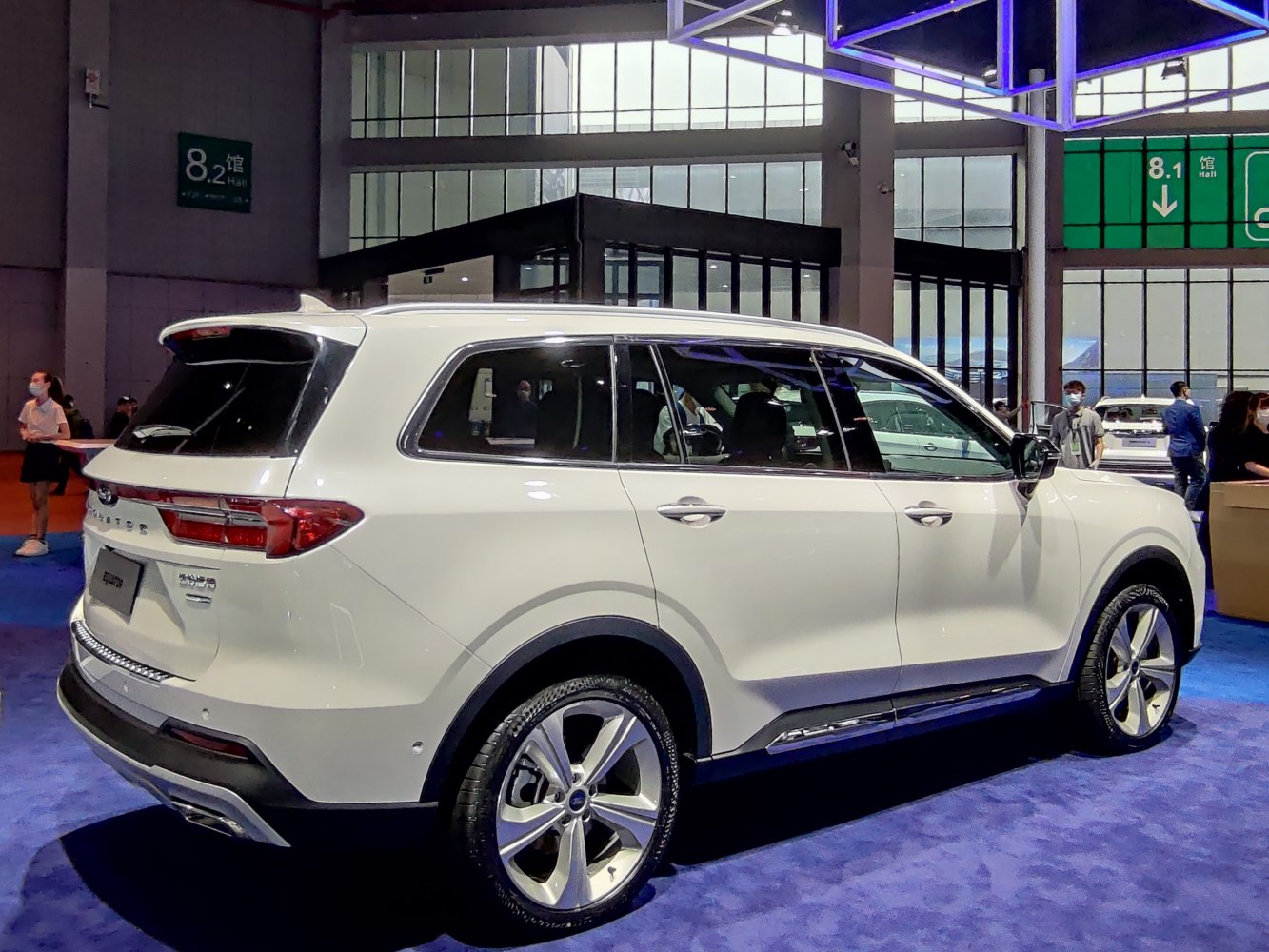 Rear-side profile of white SUV with alloy wheels and roof spoiler