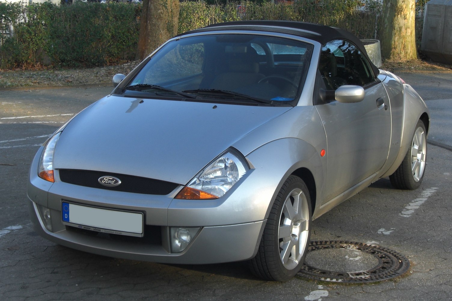 Silver convertible with soft top and distinctive headlights