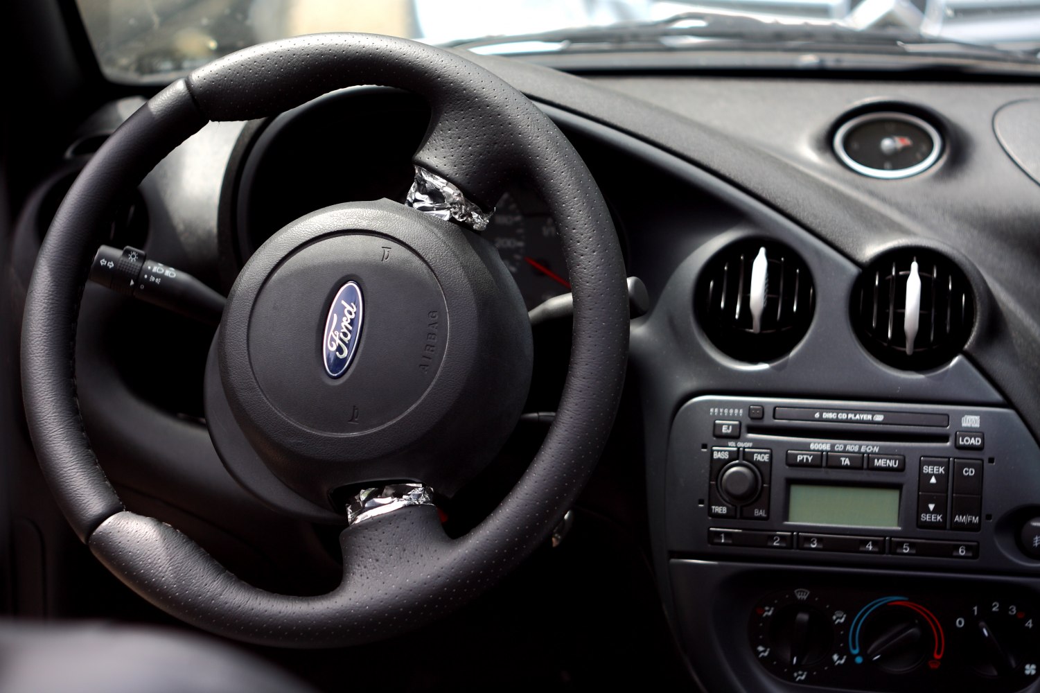 Steering wheel with Ford emblem, dashboard air vents, and car audio controls.