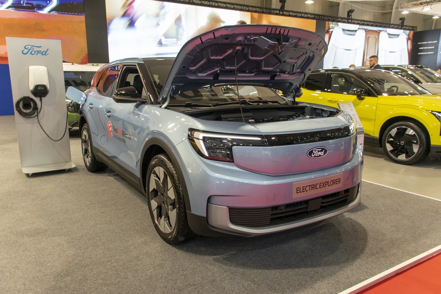 Electric SUV with open hood and nearby charging station