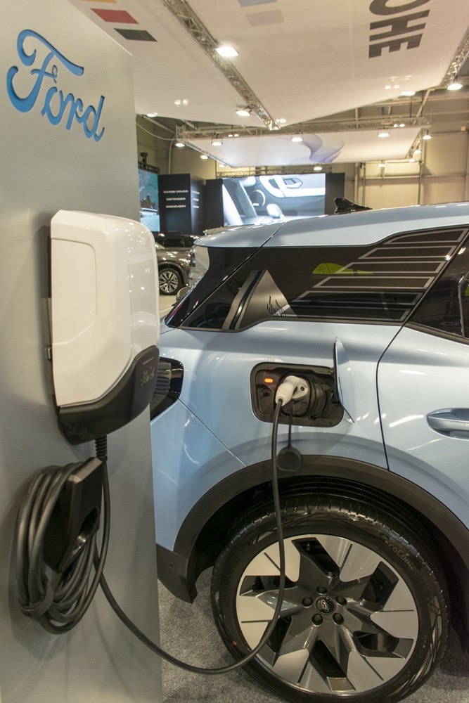 Electric SUV charging with wall-mounted charger and modern wheel design