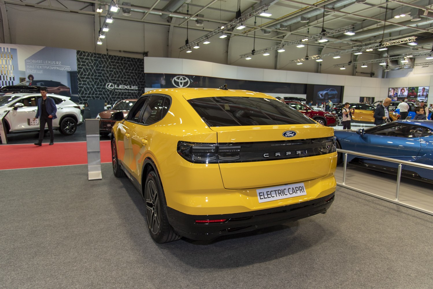 Yellow electric sedan rear with sleek horizontal taillights and tinted rear window.