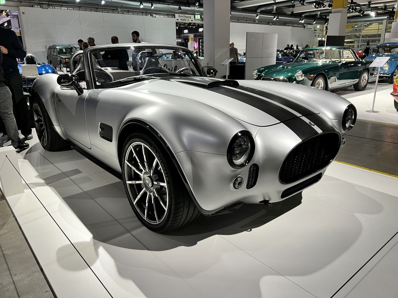 Silver open-top roadster with black racing stripes and modern alloy wheels