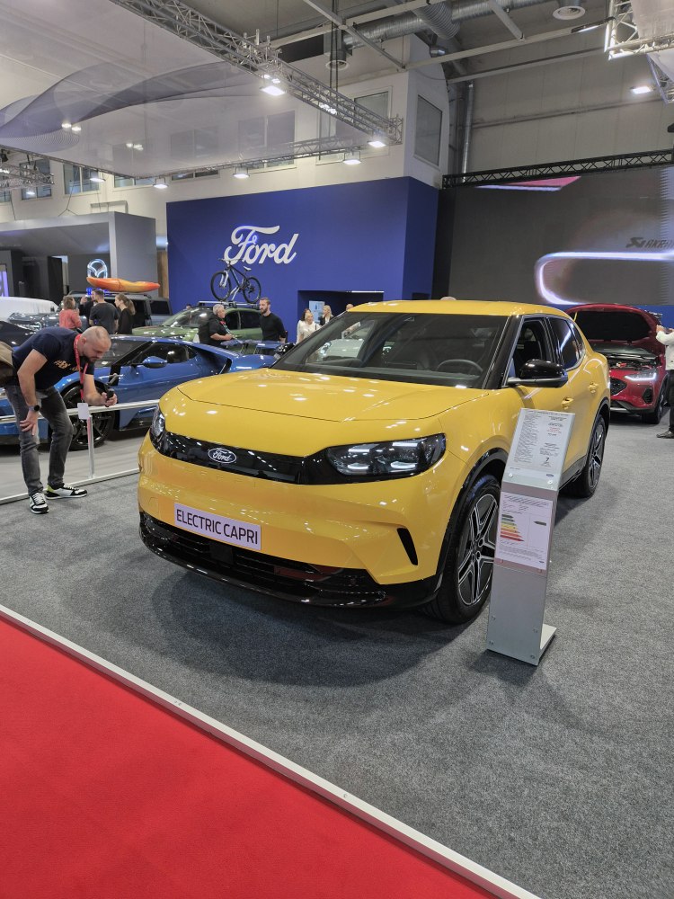 Yellow electric vehicle with sleek LED headlights and modern design at auto show