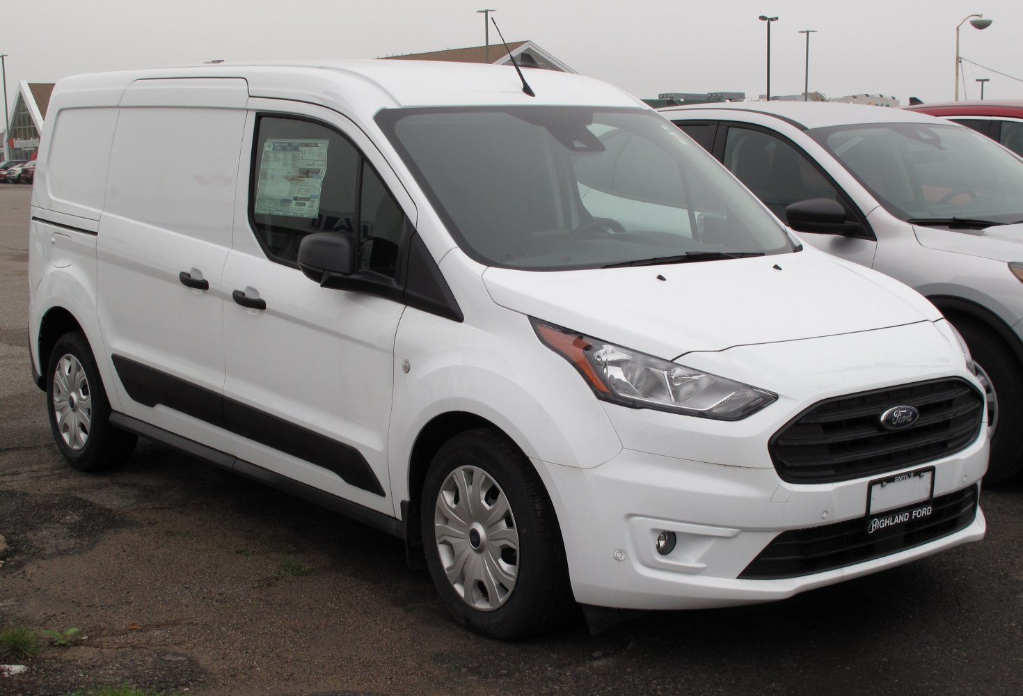 Front-side view of a white compact panel van with black trim and grille