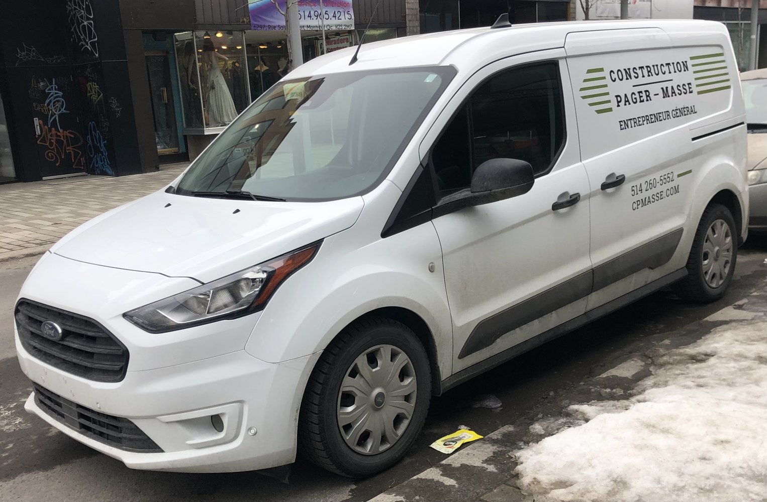 White panel van with construction signage on the side, parked in an urban setting.