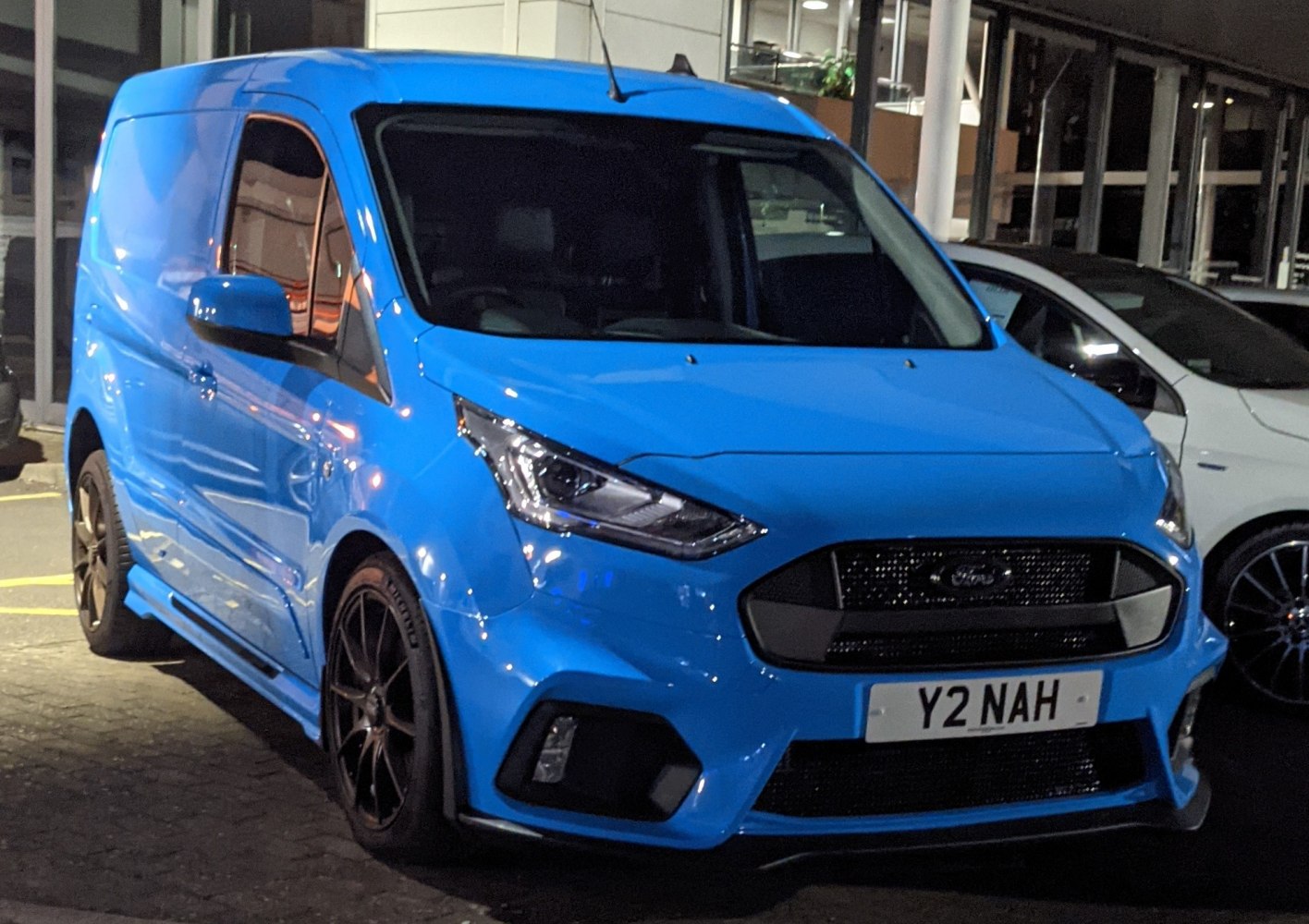 Blue panel van front with sharp headlamps and bold grille at night