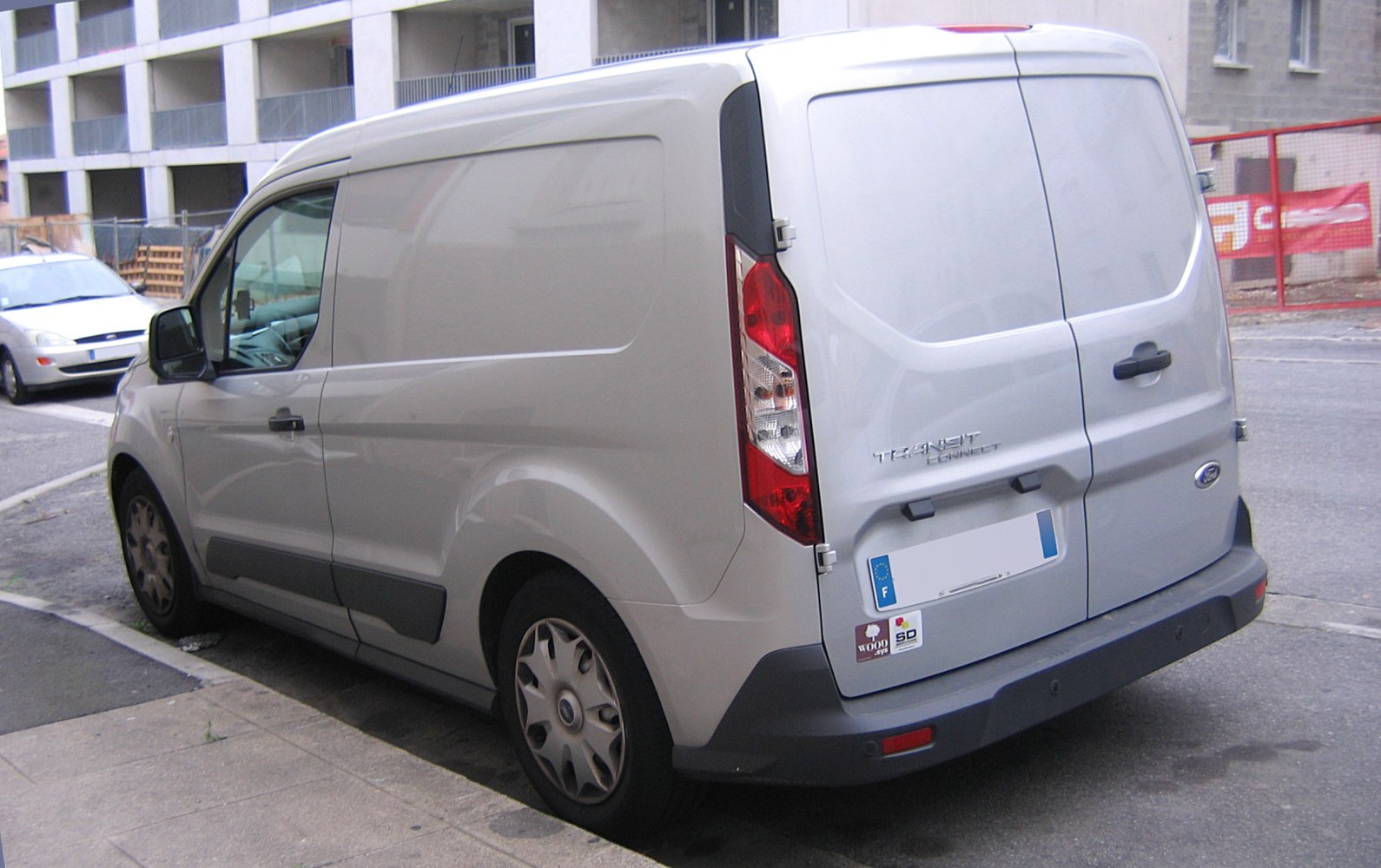 Rear side view of white panel van with sliding door and rear hinged doors