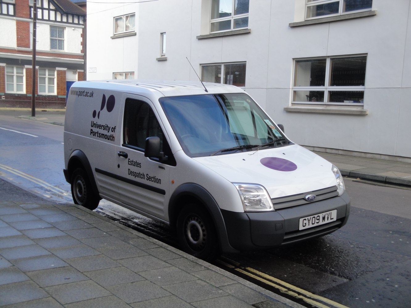 Compact panel van with delivery section and university branding.