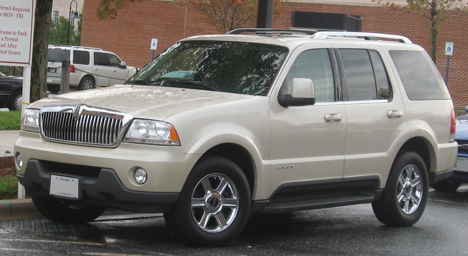 Front-side view of a beige SUV with chrome grille and roof rails