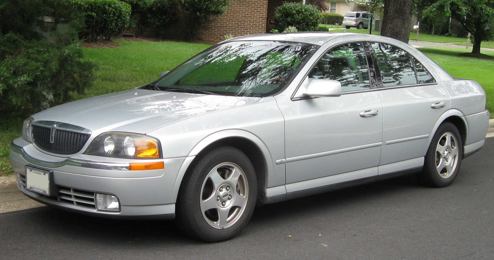 Silver full-sized sedan with classic headlights and five-spoke wheels