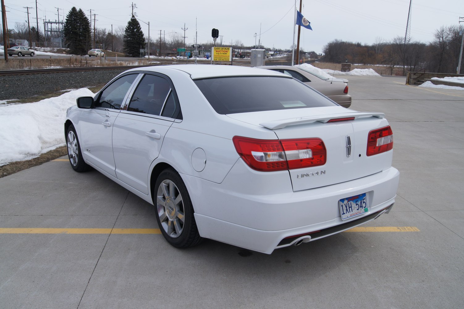 Rear and side view of white sedan with spoiler and alloy wheels