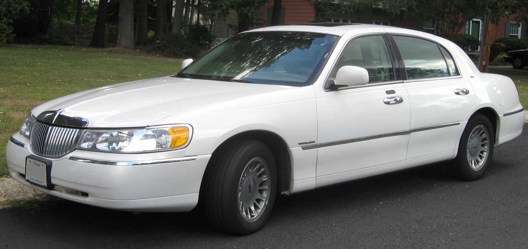 Front-side view of large white luxury sedan with chrome grille and alloy wheels.