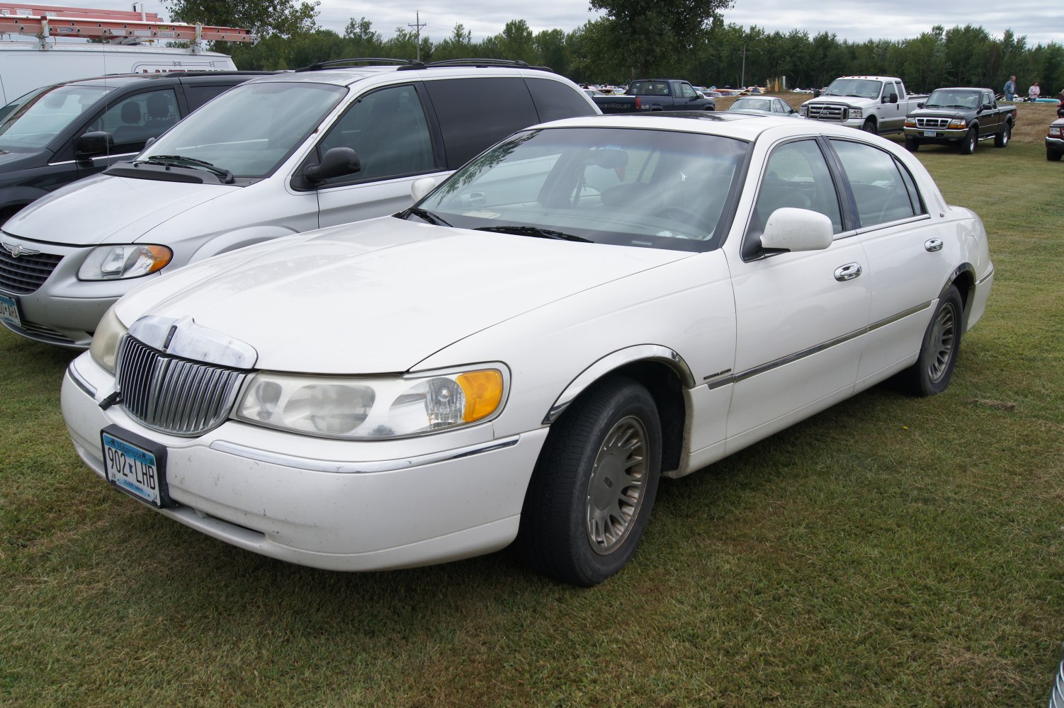Front side view of a white luxury sedan with chrome grille and classic styling