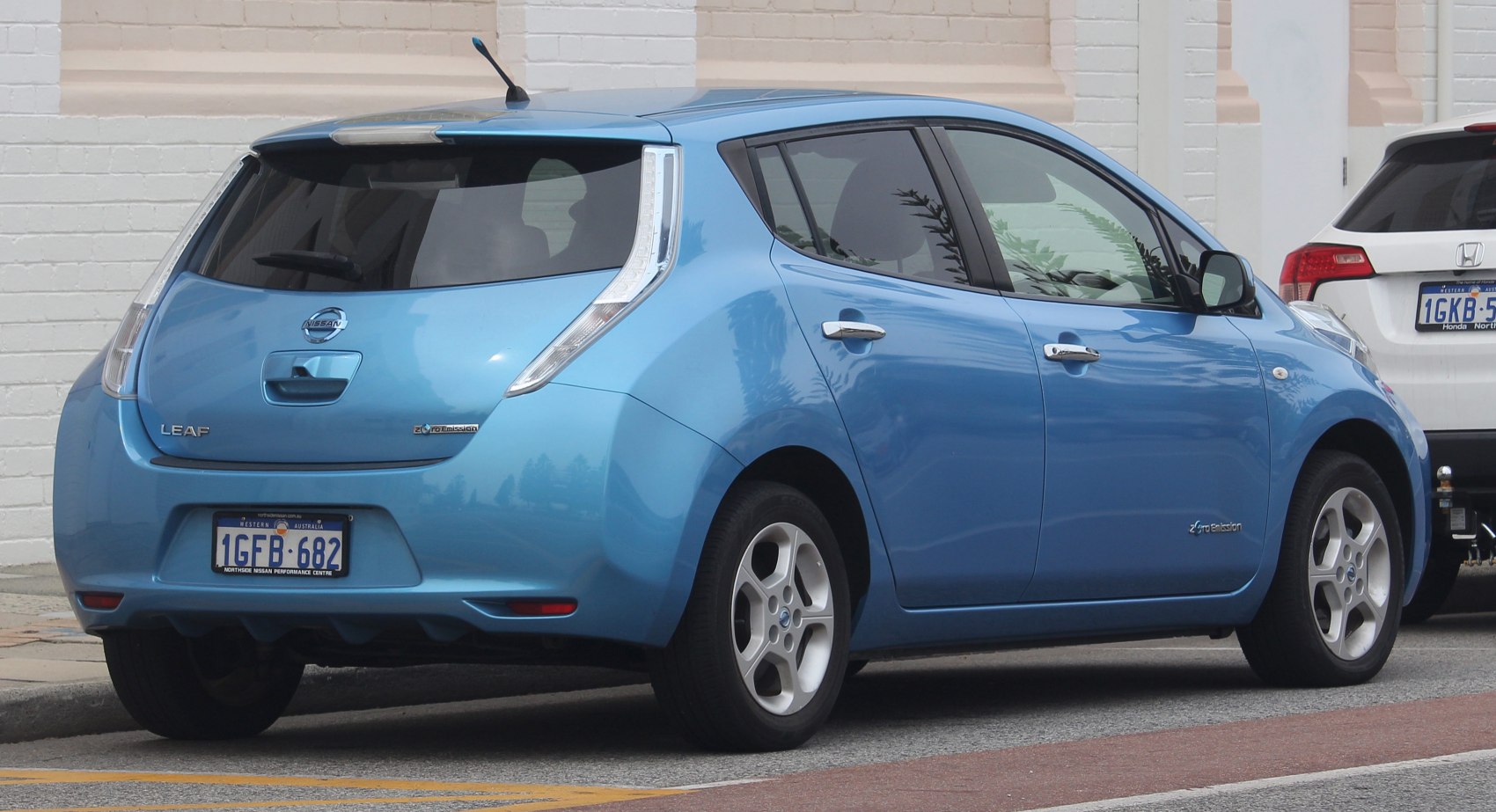 Rear side view of an electric hatchback with vertical taillights and zero emission badge.