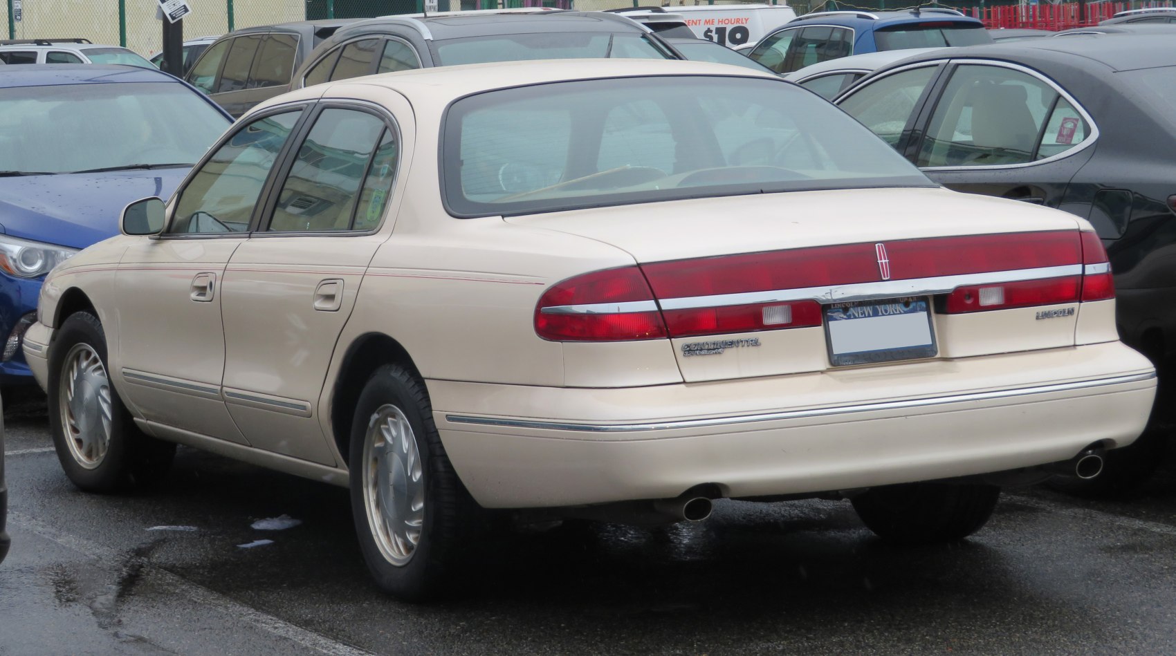 Rear view of a four-door sedan with full-width tail light and dual exhaust tips