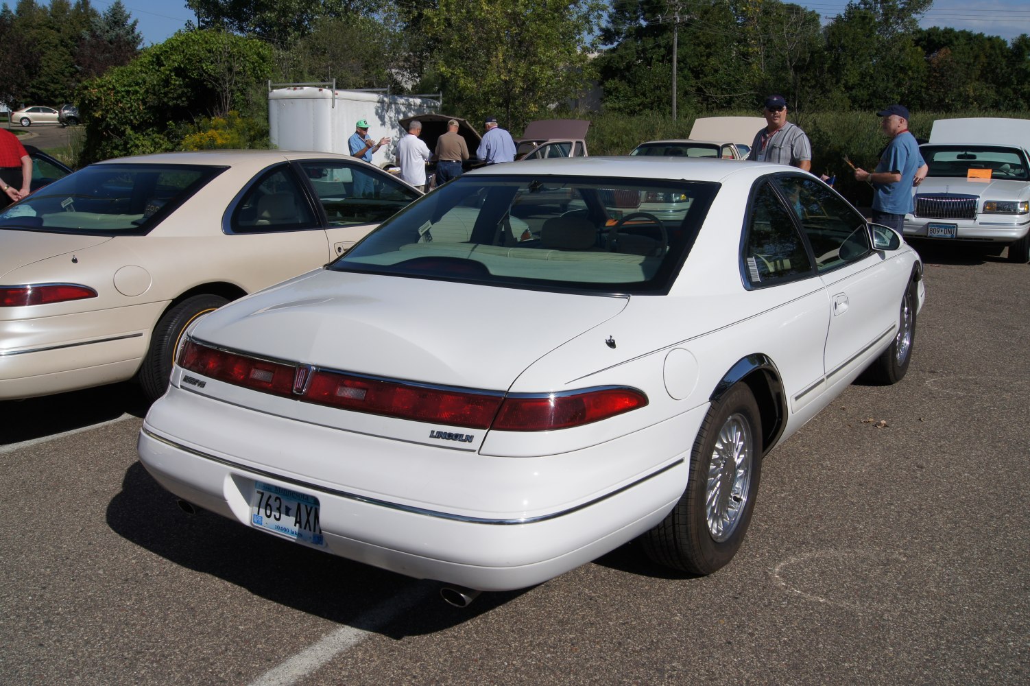 Rear view of a luxury coupe with integrated red tail lights and sleek white finish
