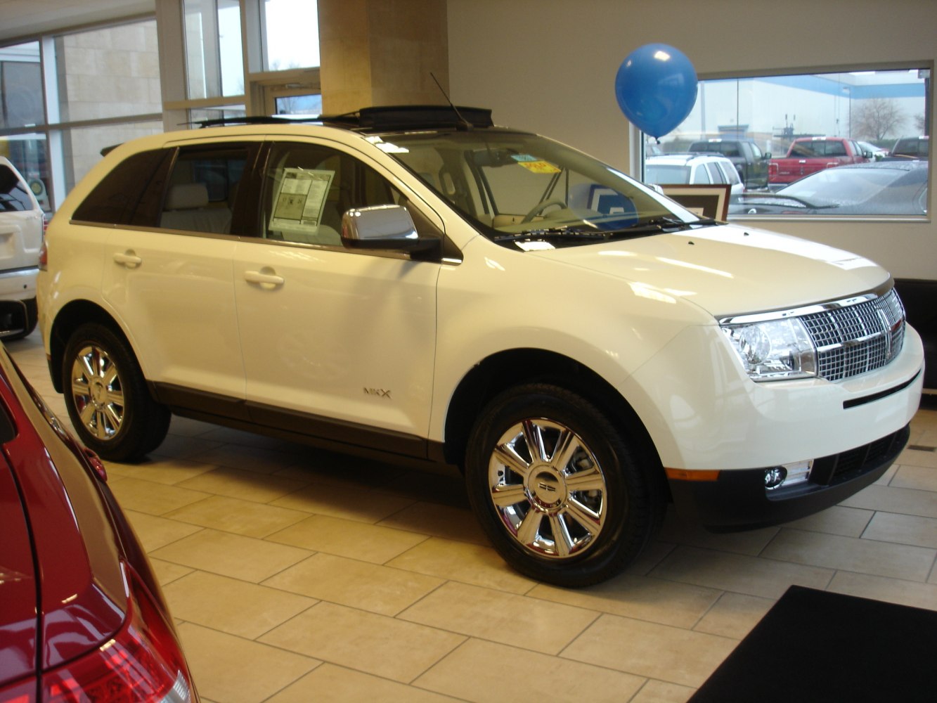 Luxury SUV with chrome wheels and mesh front grille inside showroom