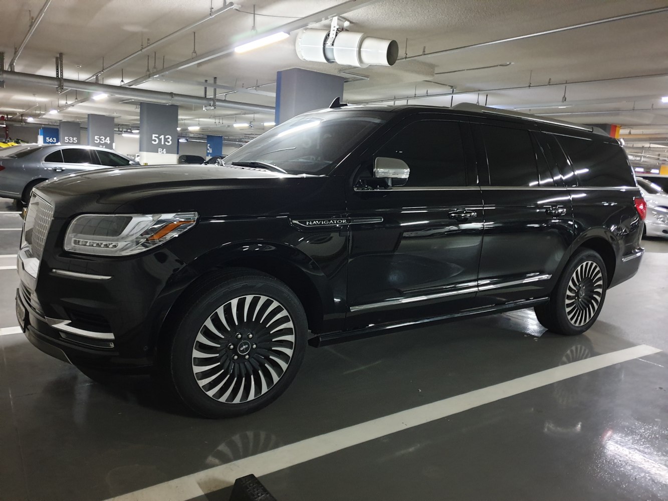 Luxury black SUV with spiral-design alloy wheels in indoor parking