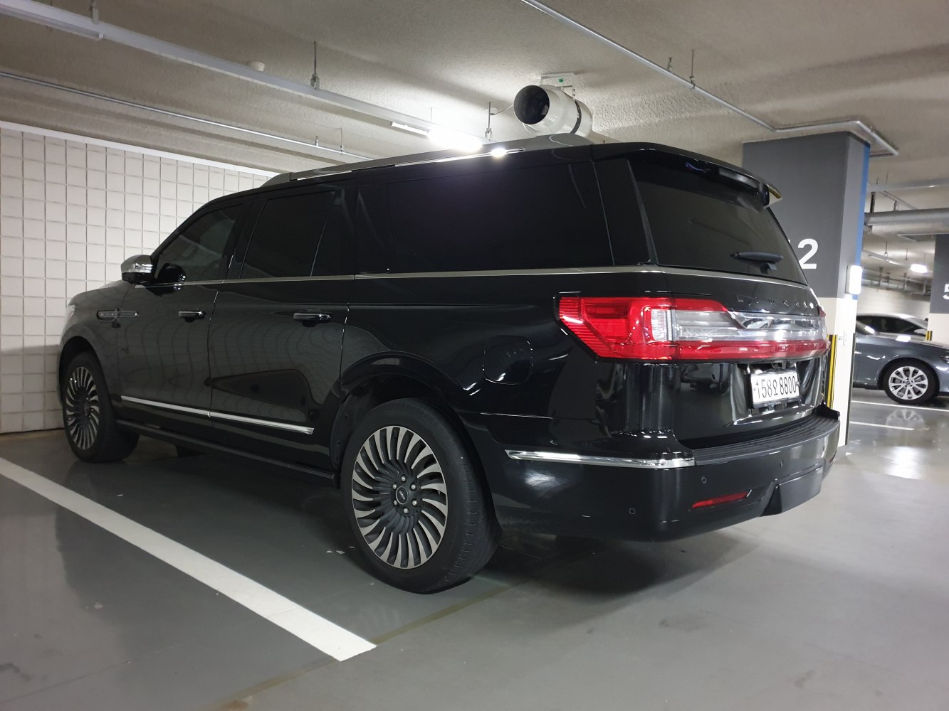 Rear and side view of a luxury black full-size SUV with large multi-spoke wheels