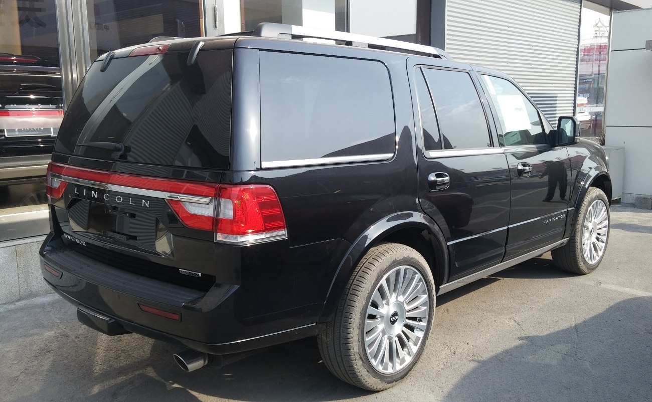 Rear and side view of large luxury SUV with tinted windows and chrome trim