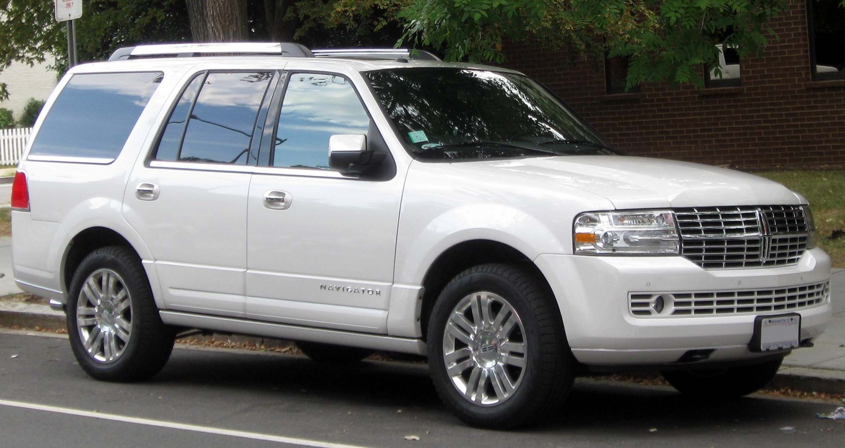 White full-size luxury SUV front and side view with chrome grille and alloy wheels