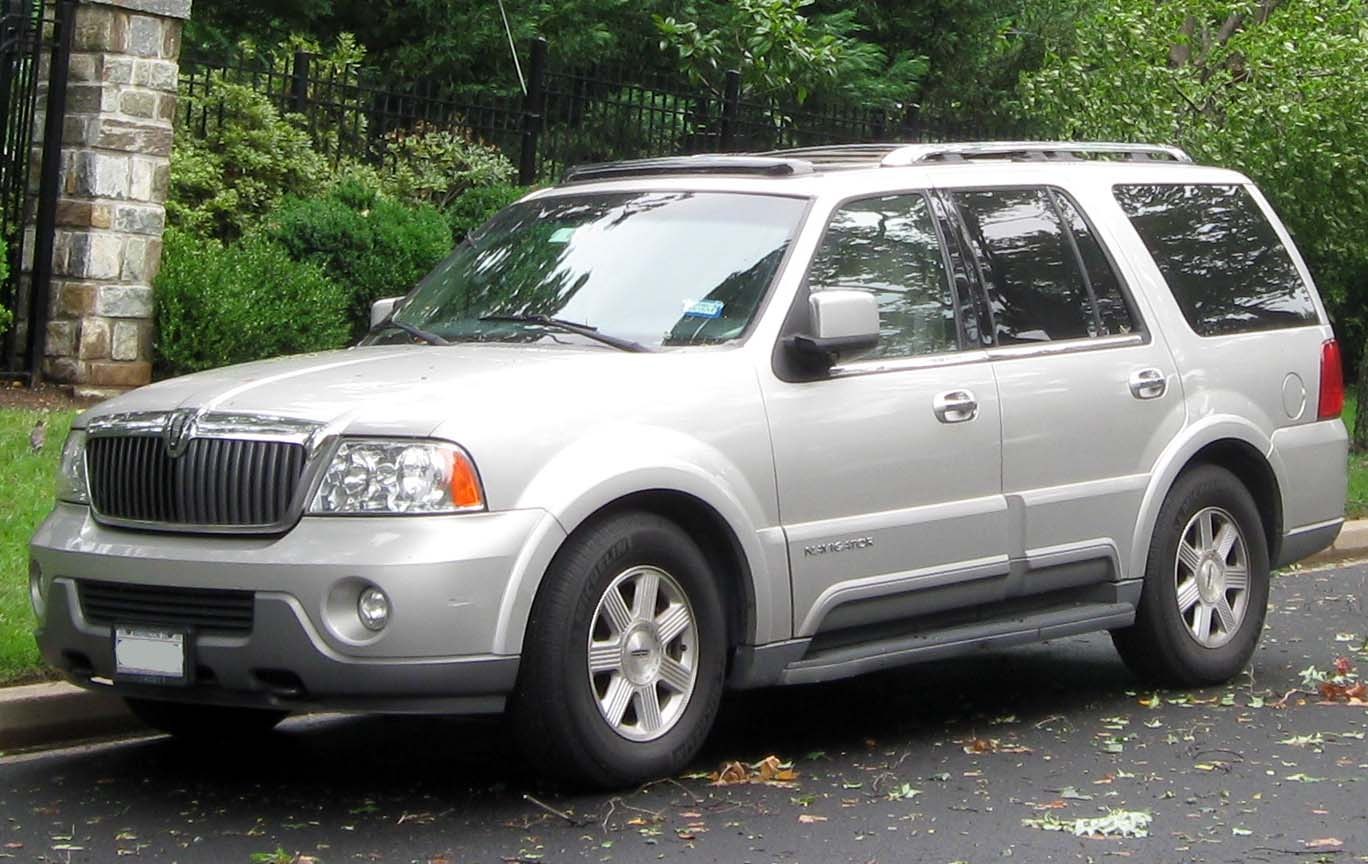 Silver SUV with chrome grille, roof rails, and five-spoke wheels