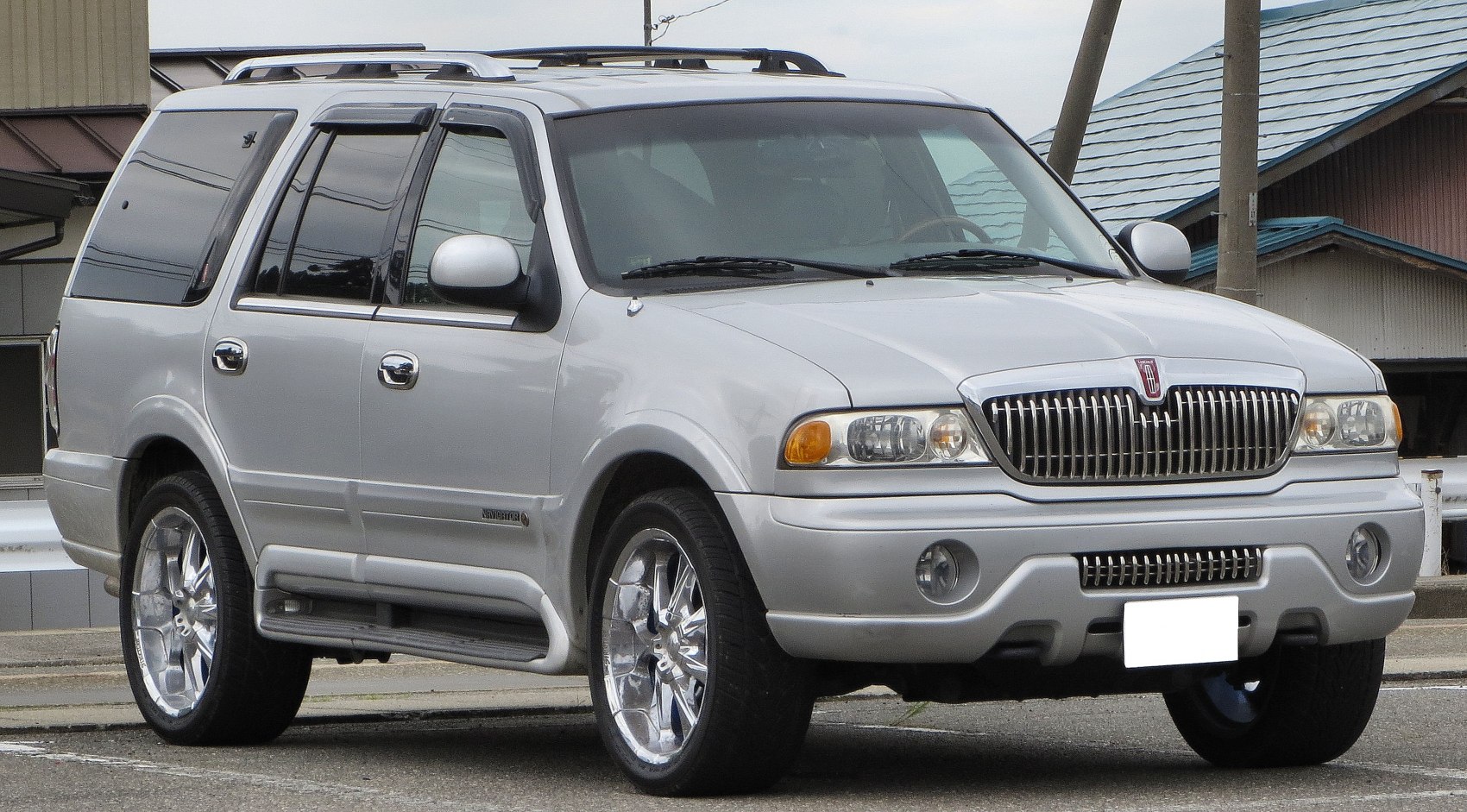 Front side view of SUV with chrome wheels and roof rack