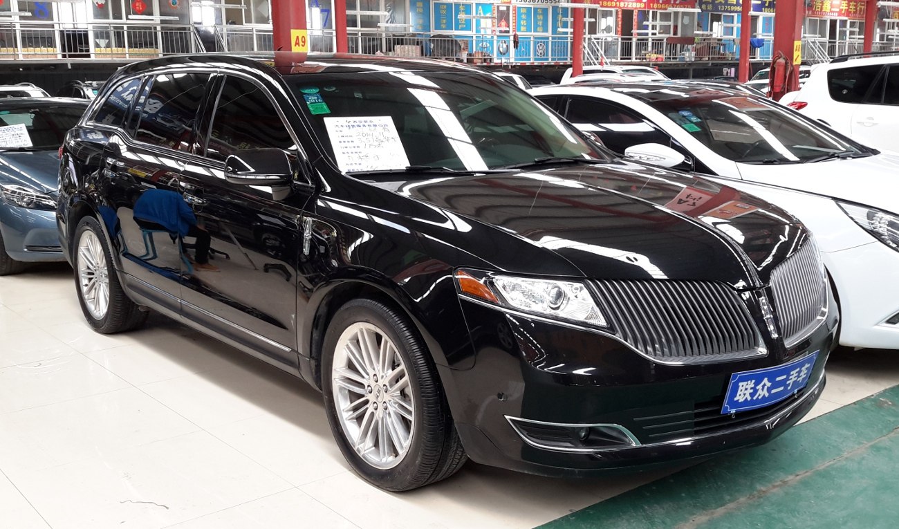 Black SUV with vertical slat grille, sleek headlights, and multi-spoke wheels.
