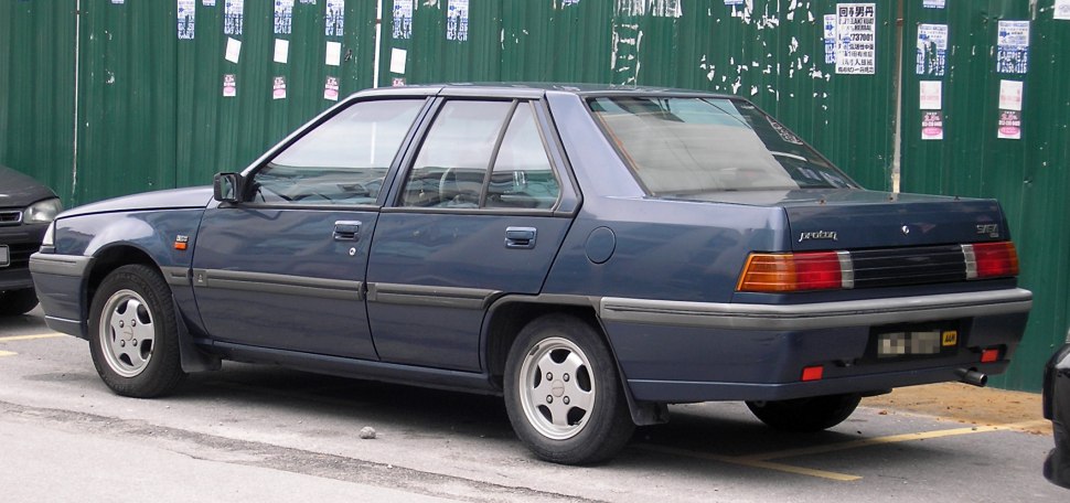 Boxy rear and side view of a classic 1990s four-door sedan.