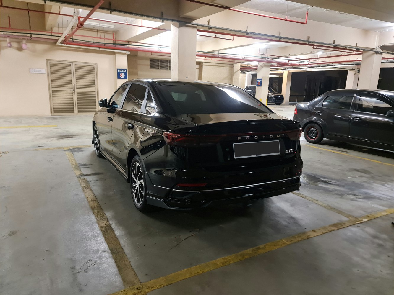 Rear-side view of black sedan with LED taillights and alloy wheels